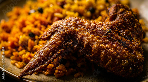 Crispy golden roasted chicken meat served with seasoned rice on a ceramic plate