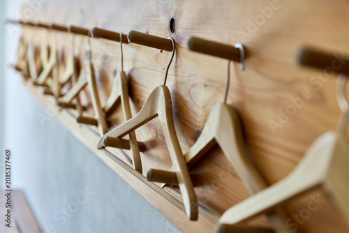 Tableau sur toile Row of empty wooden clothes hangers hanging on pegs mounted on a wooden wall panel in a cloakroom or hallway