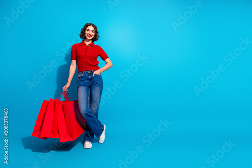 Young chic woman shopping with red bags against blue background