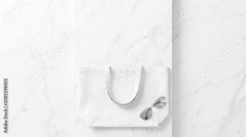 White canvas tote bag with stylish sunglasses on a clean marble surface for minimalist fashion and lifestyle branding