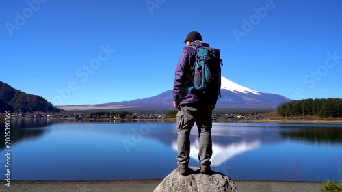 Man standing on rock by lake with mountain view