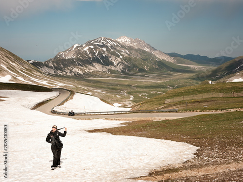 Woman standing on late spring snow with Gran Sasso massif and Campo Imperatore landscape, Abruzzo, Italy