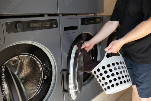 Photos A person loading clothes into the drum of a washing machine in a campground laundry area