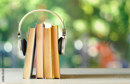audiobooks concept with  stack of books and headphones on blurred nature background,free copy space