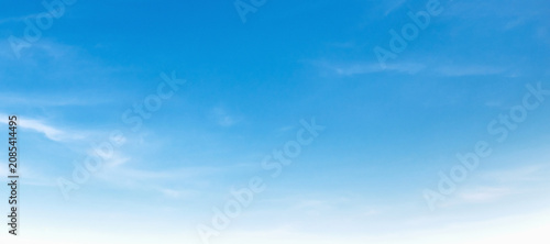Calm sky stretches wide with soft, wispy clouds