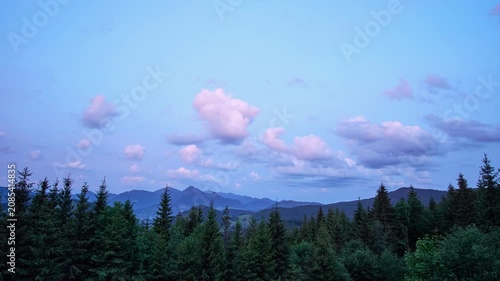 Twilight mountain panorama above evergreen forest from elevated viewpoint, with layered ridges, central peak, pastel sky, soft haze, and calm scenic wilderness mood