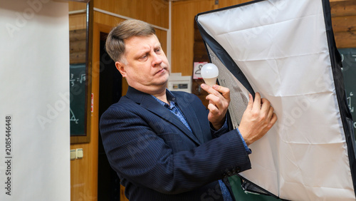 Photographer inspecting burnt out studio light bulb in professional photo studio lighting fixture.