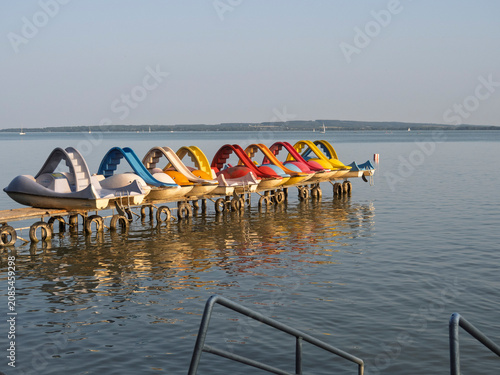 Schilderij op canvas Colorful pedal boats on a lake dock