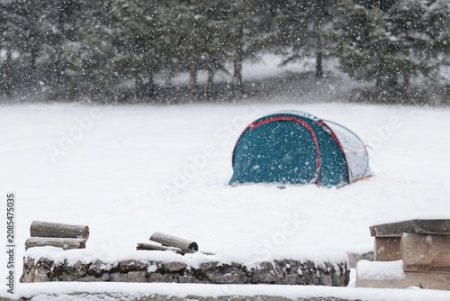 Bild auf Leinwand Amidst a heavy snowfall, a solitary tent stands resilient in a tranquil winter scene