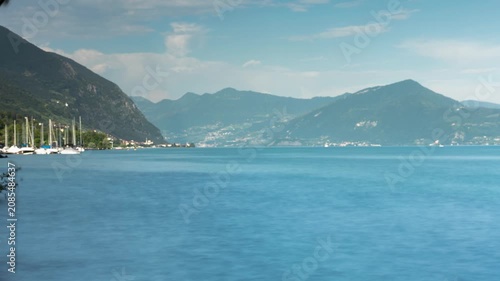 Sarnico Italy skyline timelapse with rushing clouds over scenic Lake Iseo and majestic mountains during a bright sunny summer day