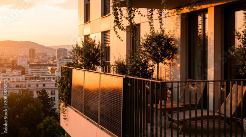 Modern apartment balcony with solar panels and city view at sunset