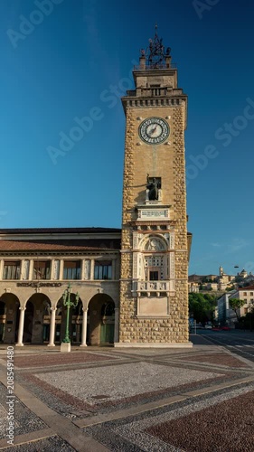 Time lapse of the Torre dei Caduti tower in Bergamo Italy under a clear blue sky with moving shadows casting over the cobblestone square