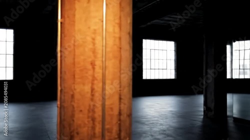 Dark industrial warehouse interior with bright windows and shadows.