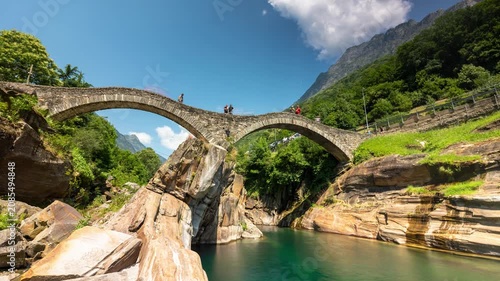 Lavertezzo Ponte dei Salti time lapse video featuring the iconic double-arch stone bridge over emerald Verzasca river with passing tourists in Switzerland