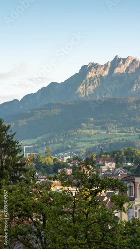 Golden hour time lapse of Mount Pilatus peak with moving shadows and changing afternoon light over the alpine city architecture of Lucerne, Switzerland