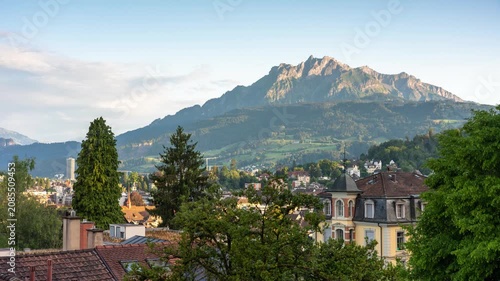 Lucerne Switzerland sunset time lapse of Mount Pilatus peak with golden hour light, moving shadows, and rushing clouds over alpine city houses
