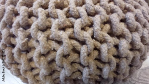 Detailed macro texture of a beige knitted pouf or braided rope cushion background