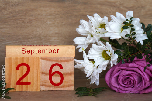 September 26, wooden calendar with fresh, colorful flowers.