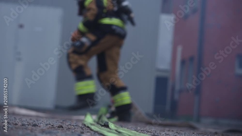 Firefighters Deploying Hose Toward Camera During Emergency Response