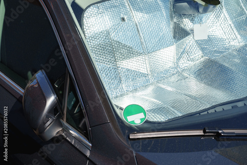 Parked SUV with reflective windshield sunshade protecting the cabin from summer heat