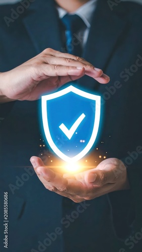 Business hands cradle glowing shield with checkmark, emphasizing protection & security