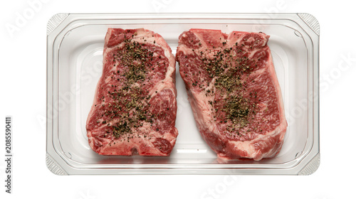 Bild auf Leinwand Two raw T-bone steaks seasoned with pepper and herbs in plastic tray