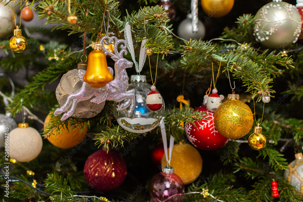 Obraz premium A Christmas tree stands with many colorful ornaments hanging from its branches. Each ornament shows different shapes and colors, celebrating the festive season and bringing joy to the home