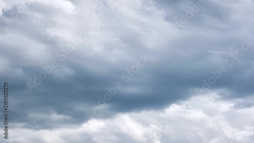 Towering cumulonimbus cloud bank shifting across blue sky with dramatic light, deep shadow, layered texture, wide horizonless backdrop, moody weather atmosphere