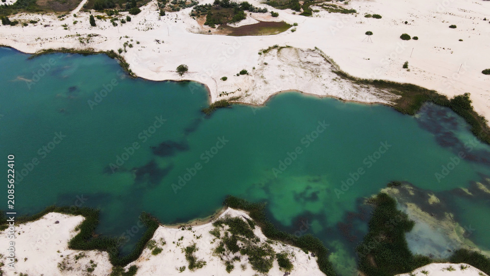 Obraz premium Emerald lake surrounded by white sand dunes, aerial view revealing calm water and natural oasis landscape