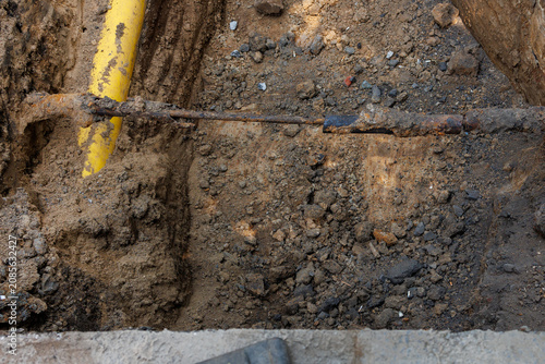 Large excavation exposing underground utility pipes during road repair
