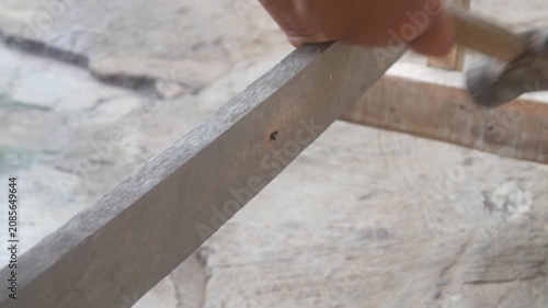 A small child's hand is holding a hammer to nail a wooden board.