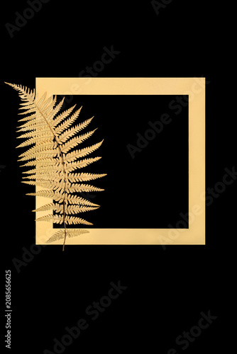 Gold fern leaf frond floral border isolated on black background with gold frame. Nature minimal zen design symbol for decorative purposes for greeting card.