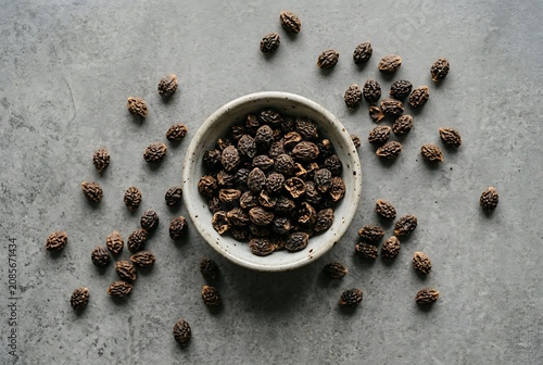 Dried haritaki fruit in a ceramic bowl on grey stone background