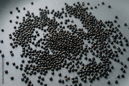 Raw black beluga lentils scattered on a grey stone surface