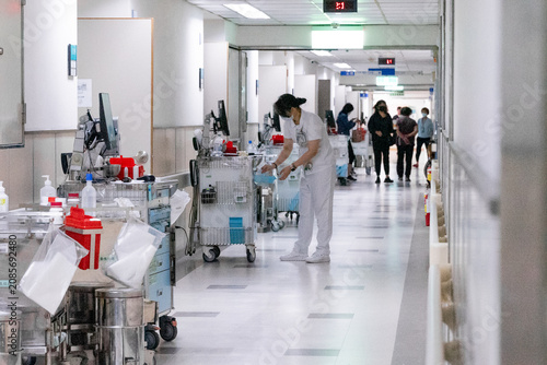 Bild auf Leinwand A nurse pushes a medical trolley through a bright hospital corridor, transporting medications and clinical supplies for patient care