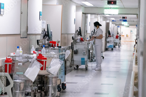 Photos A nurse pushes a medical trolley through a bright hospital corridor, transporting medications and clinical supplies for patient care