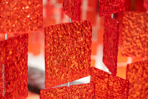 An abstract art installation featuring suspended translucent red panels with textured surfaces, creating a captivating display of light, depth, and movement. 