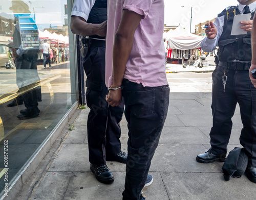 Принти на полотні A person suspected of a crime being arrested by police officers on the street