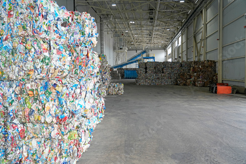 Tableau sur toile Compressed bales of diverse plastic and paper waste are stacked high inside a va