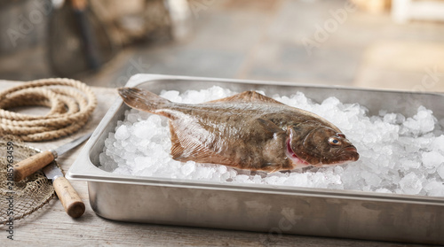 Fresh whole flounder resting on crushed ice in a stainless steel tray at a fish market