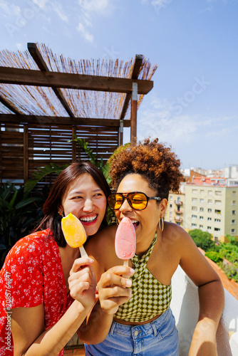 Friends enjoying refreshing fruit popsicles on sunny rooftop