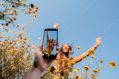 Person filming a mobile video of a smiling friend