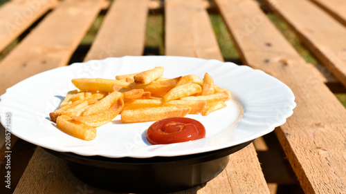 French fries on white plate on wooden background, junk food. 