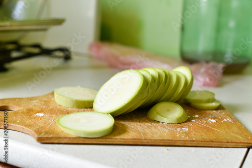 Raw zucchini slices on a wooden board with some salt in the kitchen. Ukrainian cuisine
