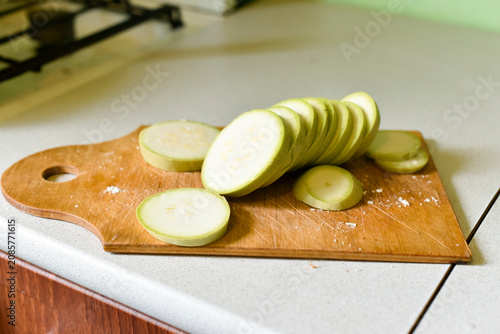 Raw zucchini slices on a wooden board with some salt in the kitchen. Ukrainian cuisine