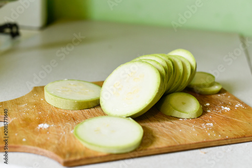 Raw zucchini slices on a wooden board with some salt in the kitchen. Ukrainian cuisine