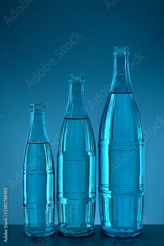 Three backlit bottles, Cyan background