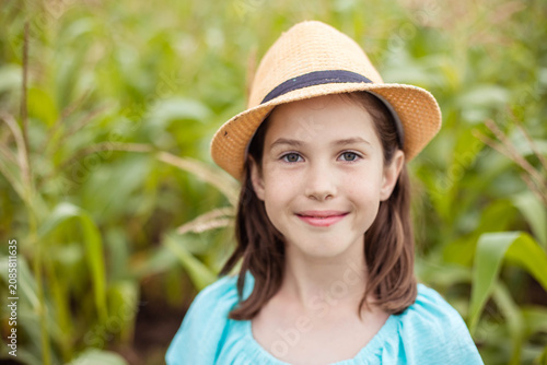 Close-up portrait of cute cute girl in hat on summer landscape background