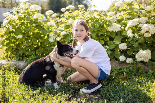 Teenage girl playing with her dog in the yard of her house on a summer day
