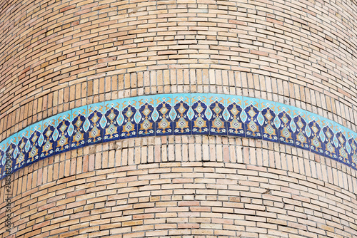 Close-up of ancient minaret with a band of decorative blue tiles.